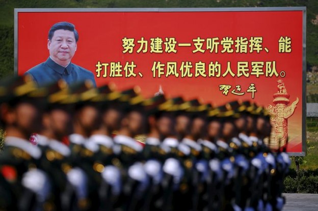 A picture of Chinese President Xi is seen on a billboard behind soldiers of China's People's Liberation Army marching during a training session at a military base in Beijing