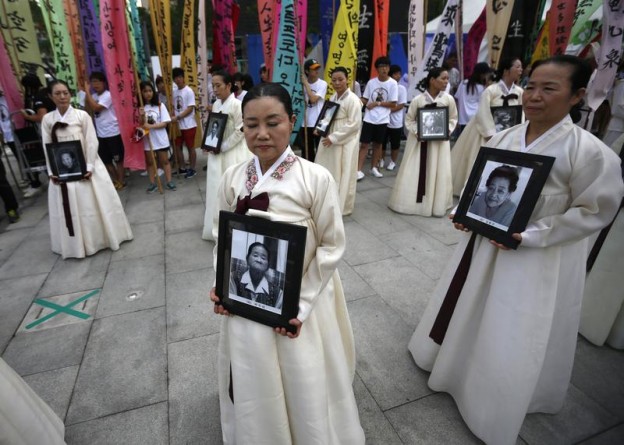 Participants carry the portraits of Korean women who were made sex slaves by the Japanese military during World War II at a requiem ceremony for former comfort woman Lee Yong-nyeo in central Seoul August 14, 2013. Lee, who was one of the few surviving sex slaves, or "comfort women", for wartime Japanese soldiers, died on Sunday, according to local media. Japanese Prime Minister Shinzo Abe may make a ritual offering to Yasukuni Shrine, seen as a symbol of Japan's former militarism, on Thursday, the emotive anniversary of Japan's defeat in World War Two, media said on Wednesday. A similar move in April infuriated China and South Korea, both victims of wartime aggression. REUTERS/Kim Hong-Ji (SOUTH KOREA - Tags: POLITICS TPX IMAGES OF THE DAY CIVIL UNREST) - RTX12KU7