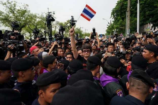 Pro-democracy activist Rome Rangsiman (C) holds up a Thailand flag as anti-government protesters gather during a protest to demand that the military government hold a general election by November, in Bangkok, Thailand, May 22, 2018. REUTERS/Athit Perawongmetha - RC1CA4507CE0