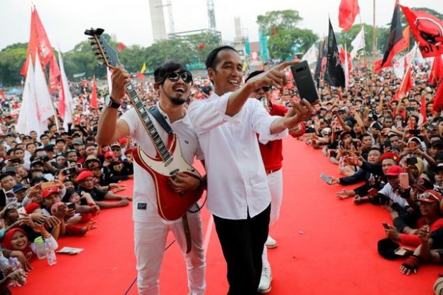 Indonesia's president and presidential candidate for the next election Joko Widodo takes selfie pictures with Indonesian band called Radja during a campaign rally in Solo, Indonesia, April 9, 2019. REUTERS/Willy Kurniawan - RC1CEC85B320